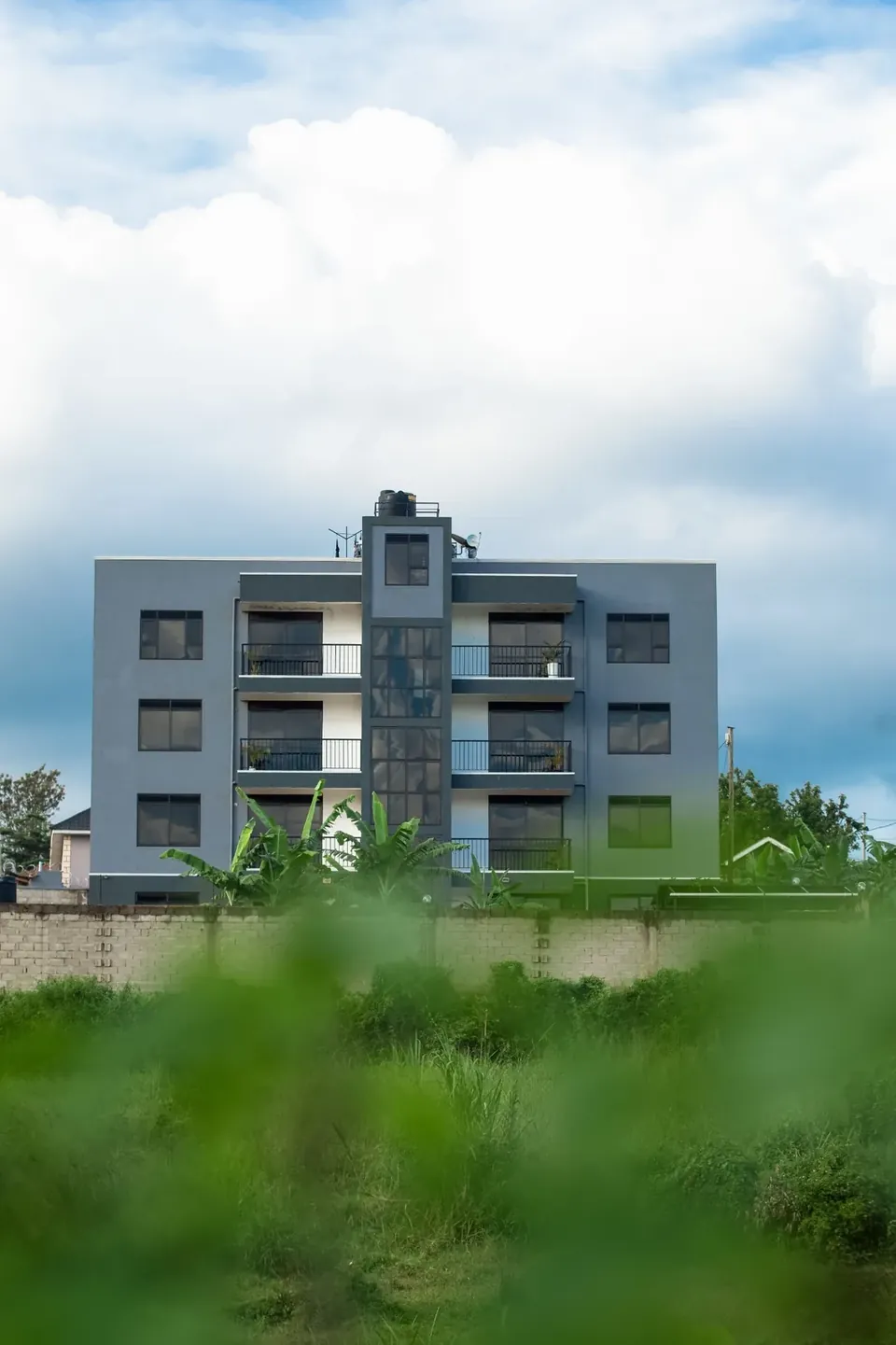Exterior of the Behomu Apartments building in Kira, Kampala, framed by greenery