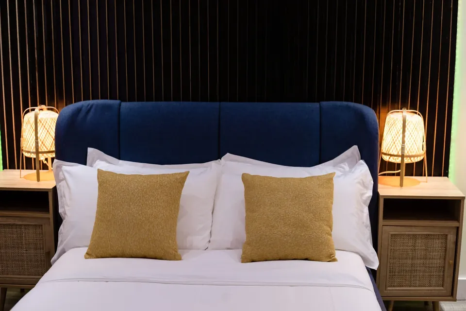 Blue headboard, crisp white linen and mustard cushions in a Behomu bedroom