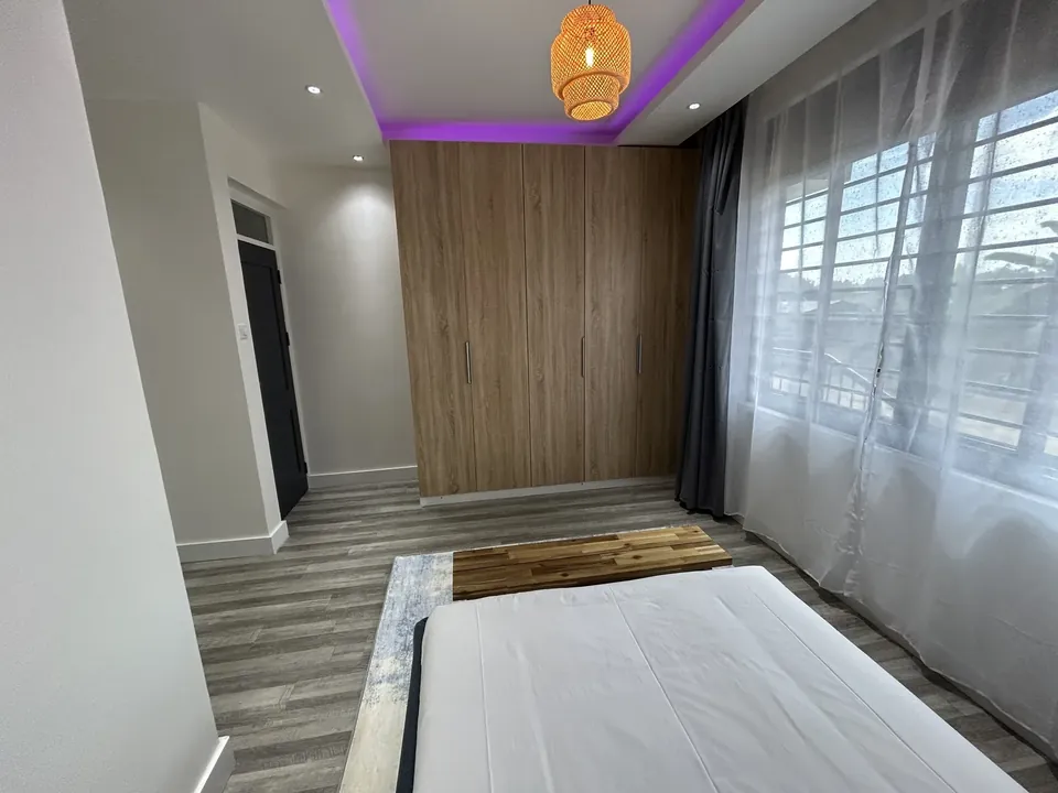 Bedroom with full-height fitted wooden wardrobe and large windows