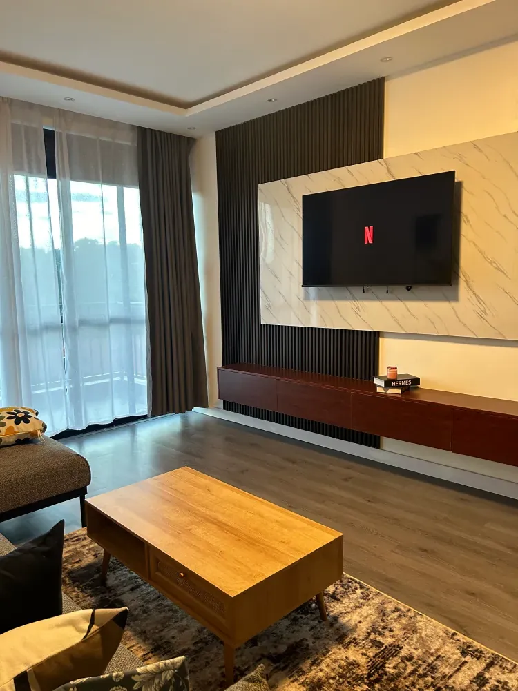 Living room with marble-effect TV wall, wooden coffee table and balcony doors