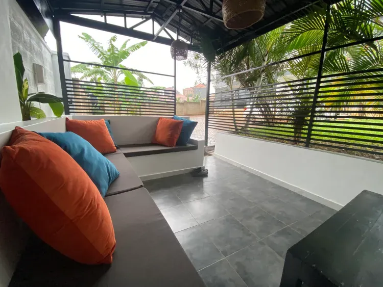 Covered terrace lounge with built-in seating and tropical plants at Behomu Apartments
