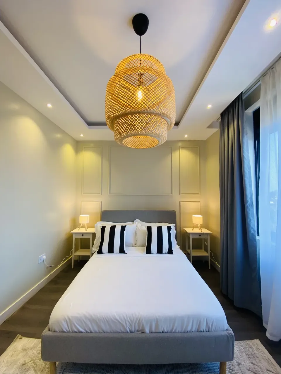 Bedroom with rattan pendant light and grey upholstered double bed