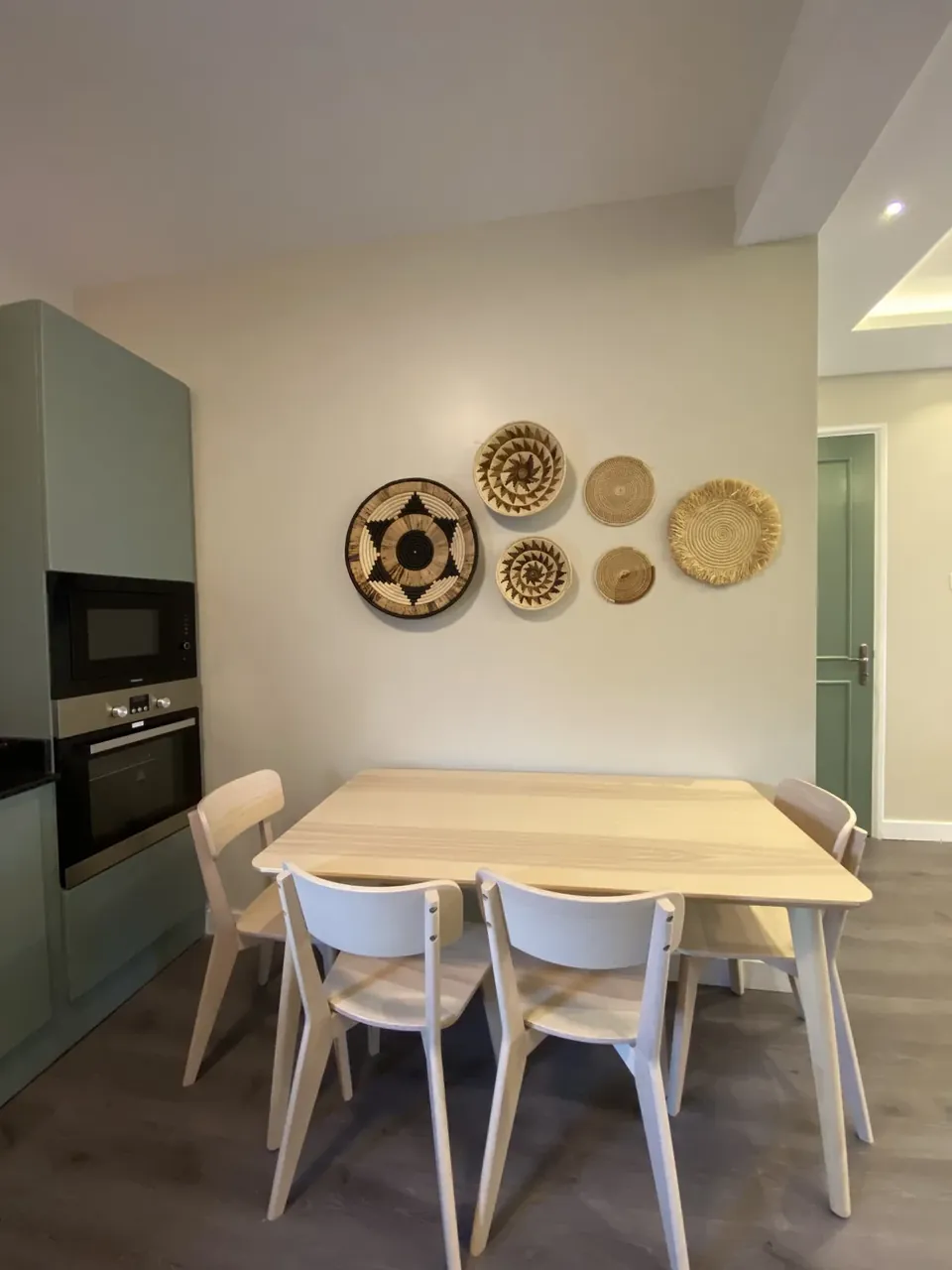 Dining table with woven basket wall decor beside the kitchen