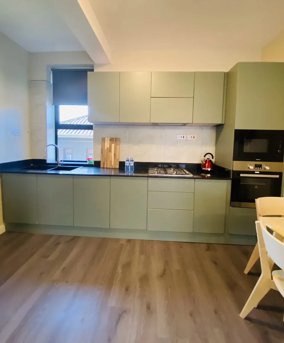Modern sage-green kitchen with built-in oven and microwave