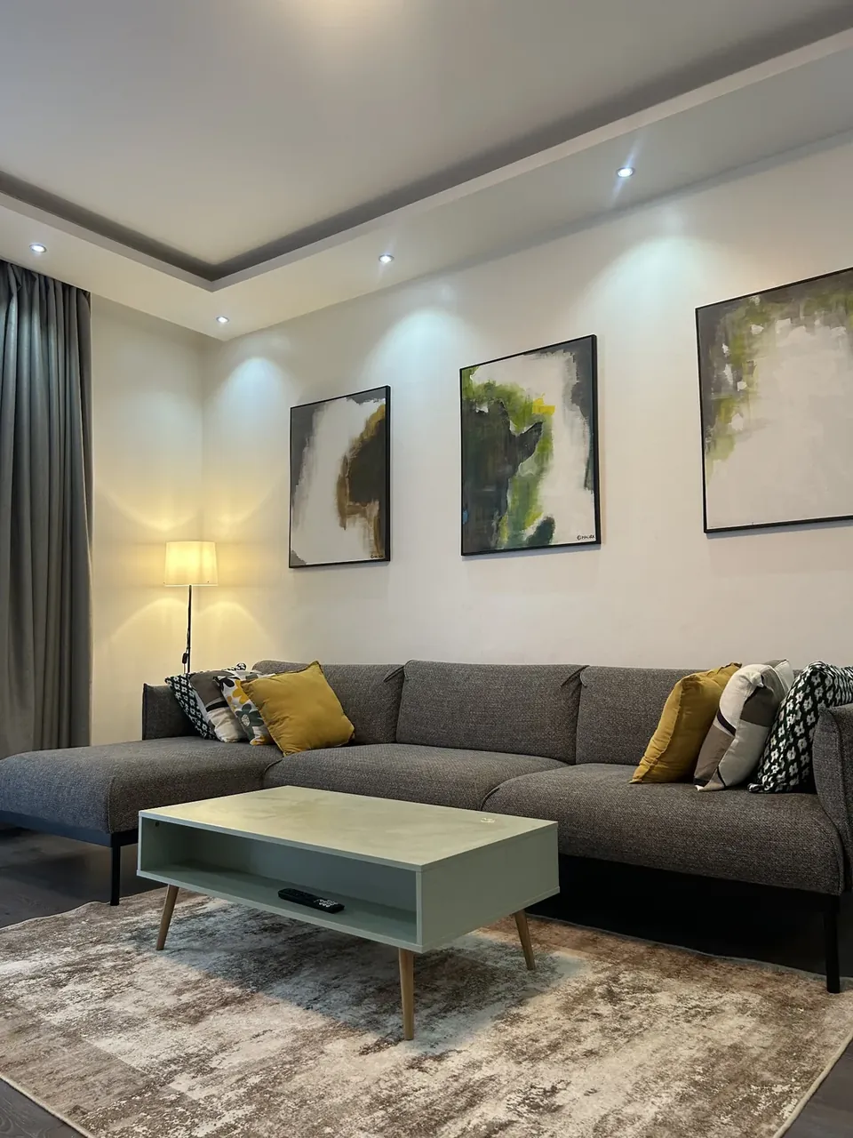 Living room with grey sectional sofa, mint coffee table and abstract artwork