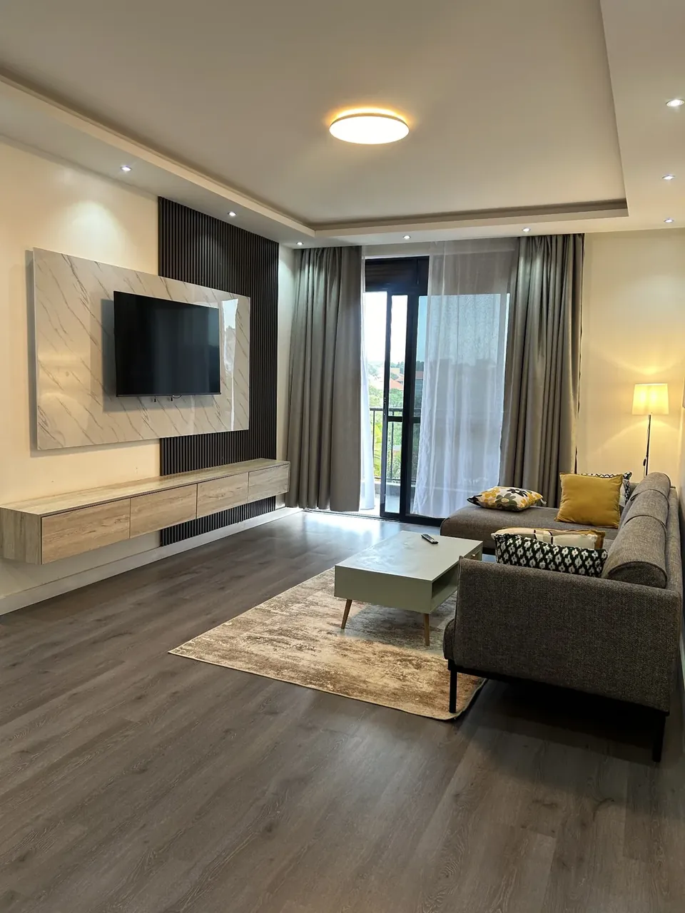 Living room with wall-mounted TV, rug and balcony doors
